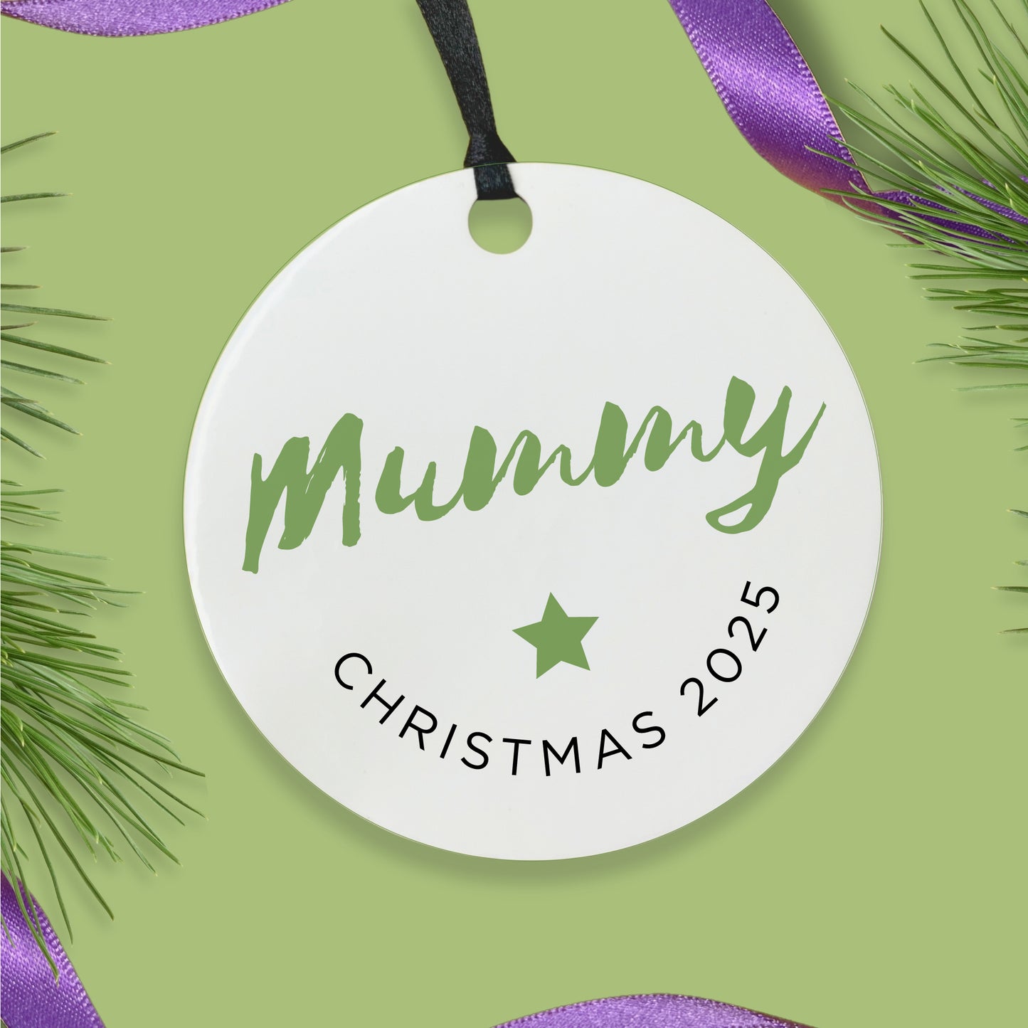 Round white bauble with choice of name and Christmas 2025 text on a green background with purple ribbon and pine branches.