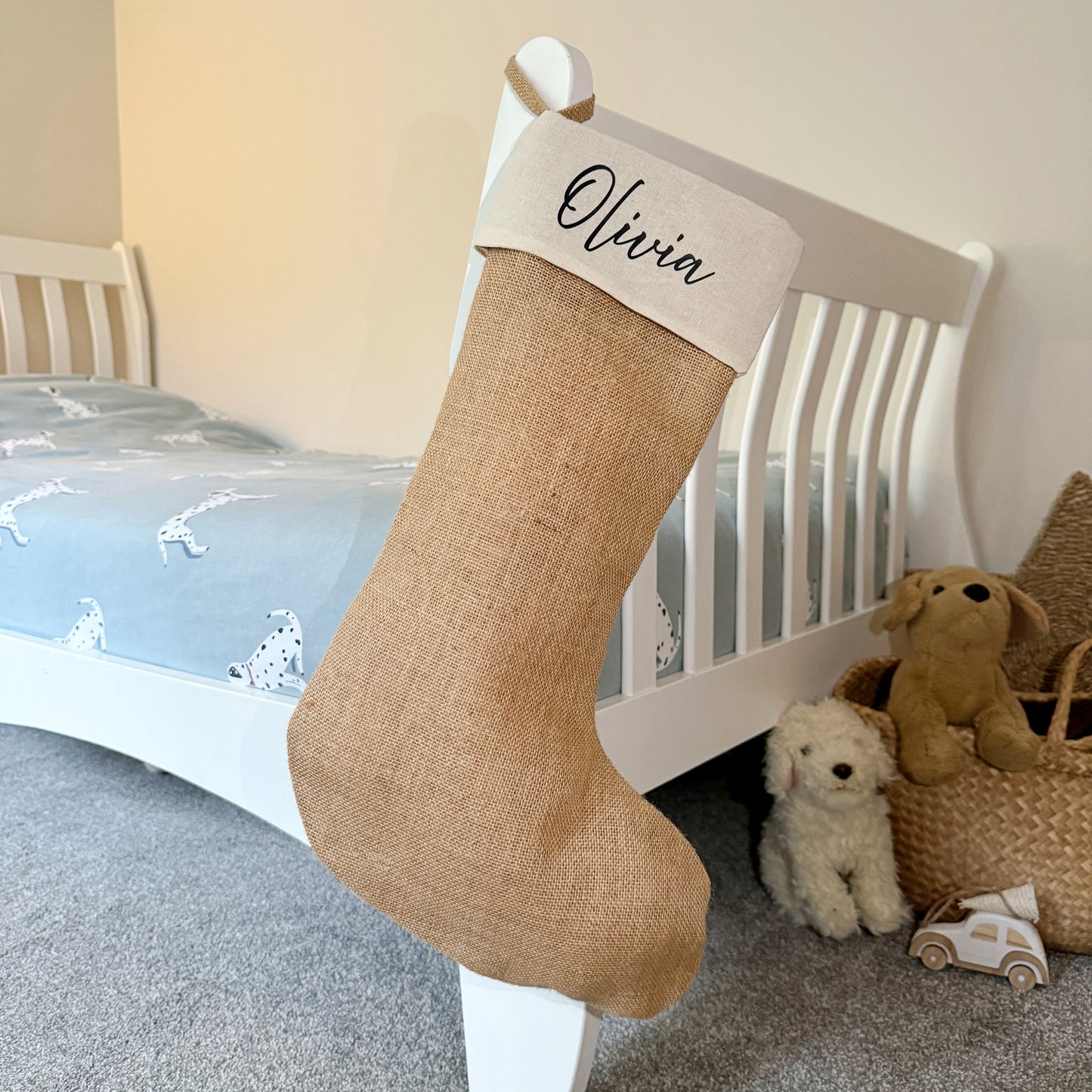 Jute Christmas stocking with 'Olivia' on a bed in a child's room.