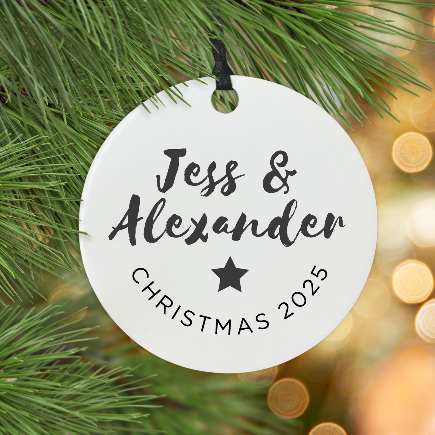 Personalised Christmas ornament with names and 'Christmas 2025' text, hanging on a tree.
