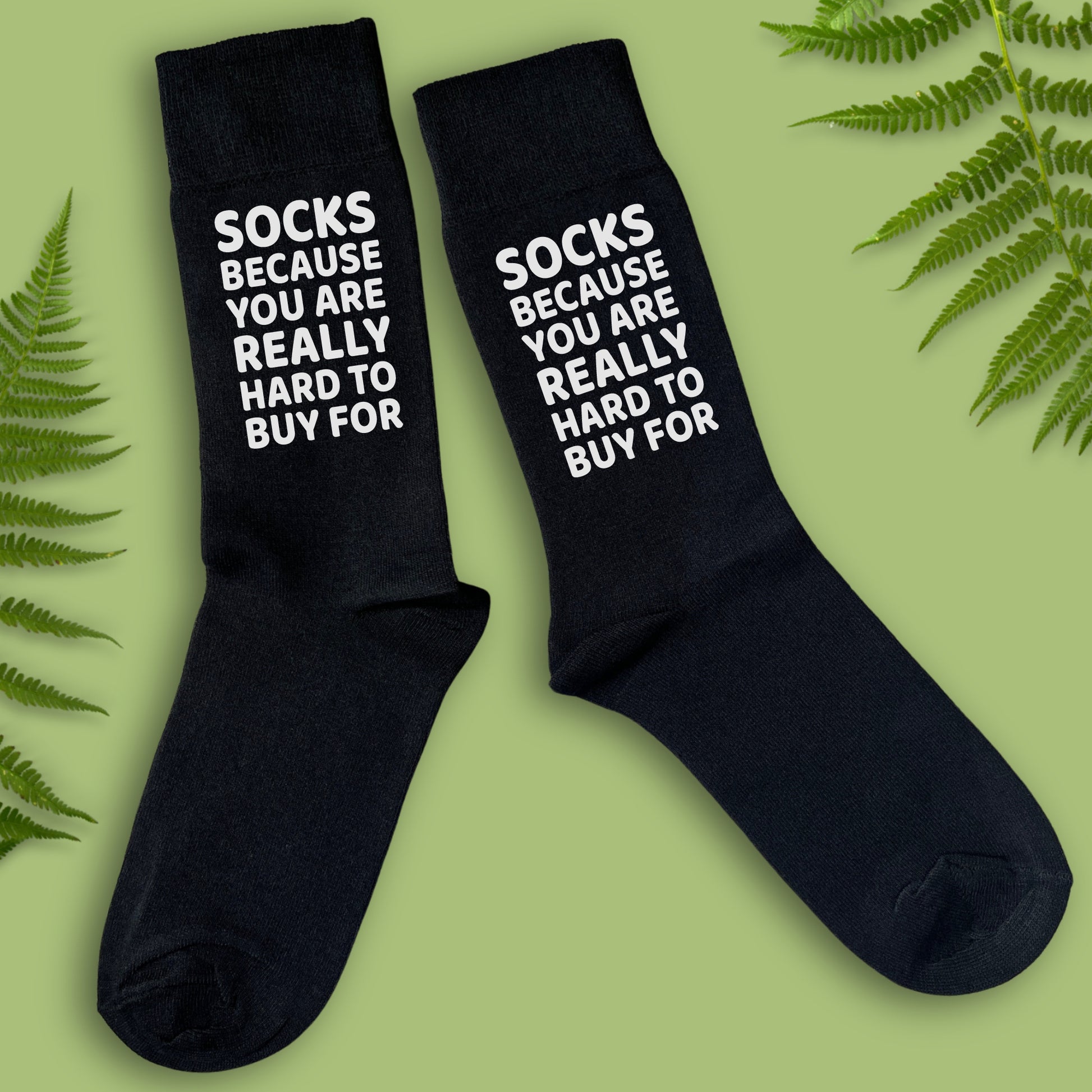 A pair of black socks with the text 'SOCKS BECAUSE YOU ARE REALLY HARD TO BUY FOR' 