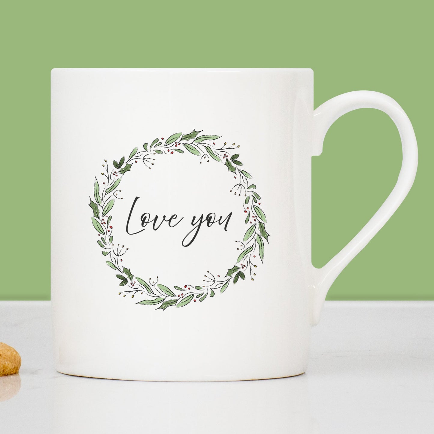 White mug with 'Love you' text and floral wreath on a green background