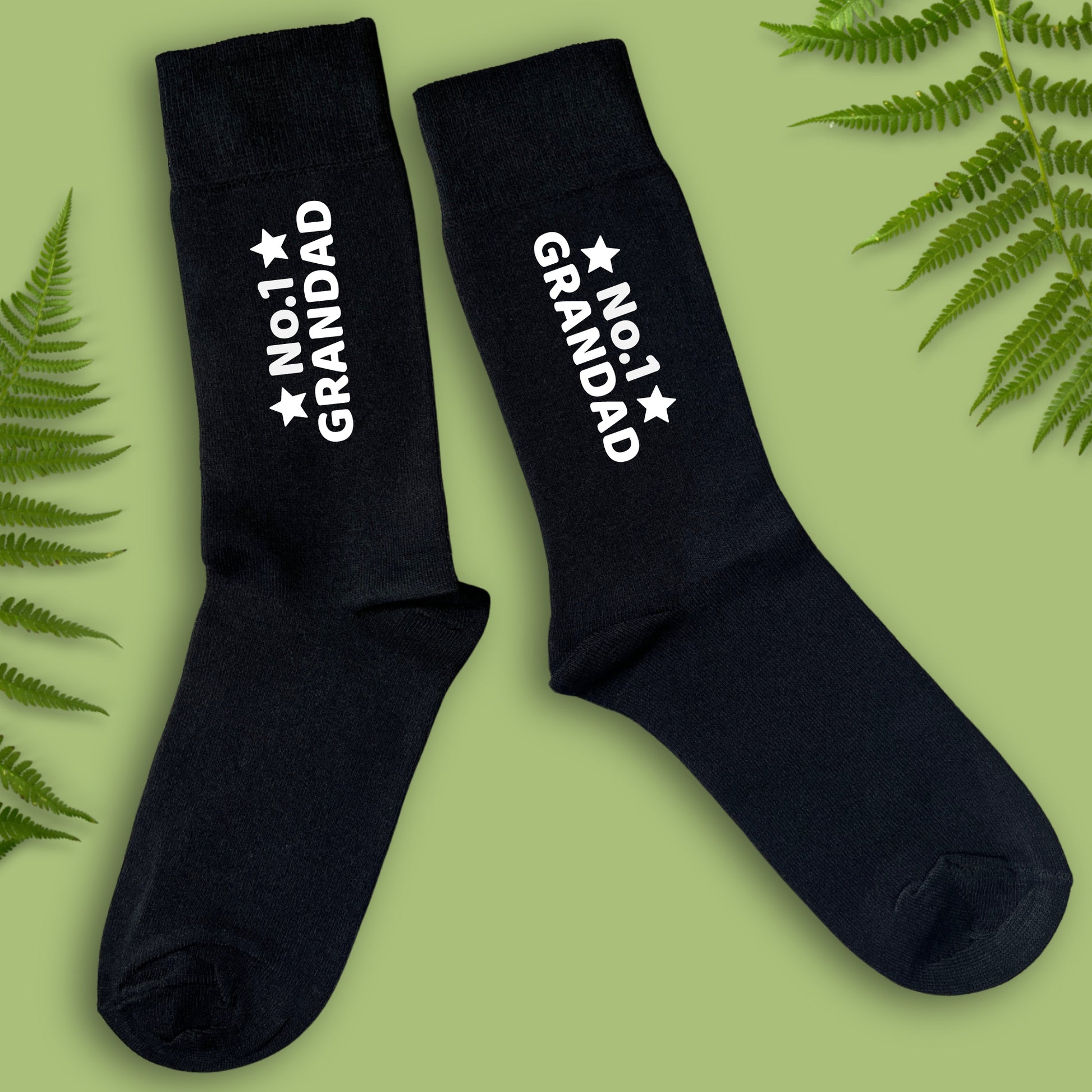 Black socks with 'No.1 Grandad' text on a green background with fern leaves.