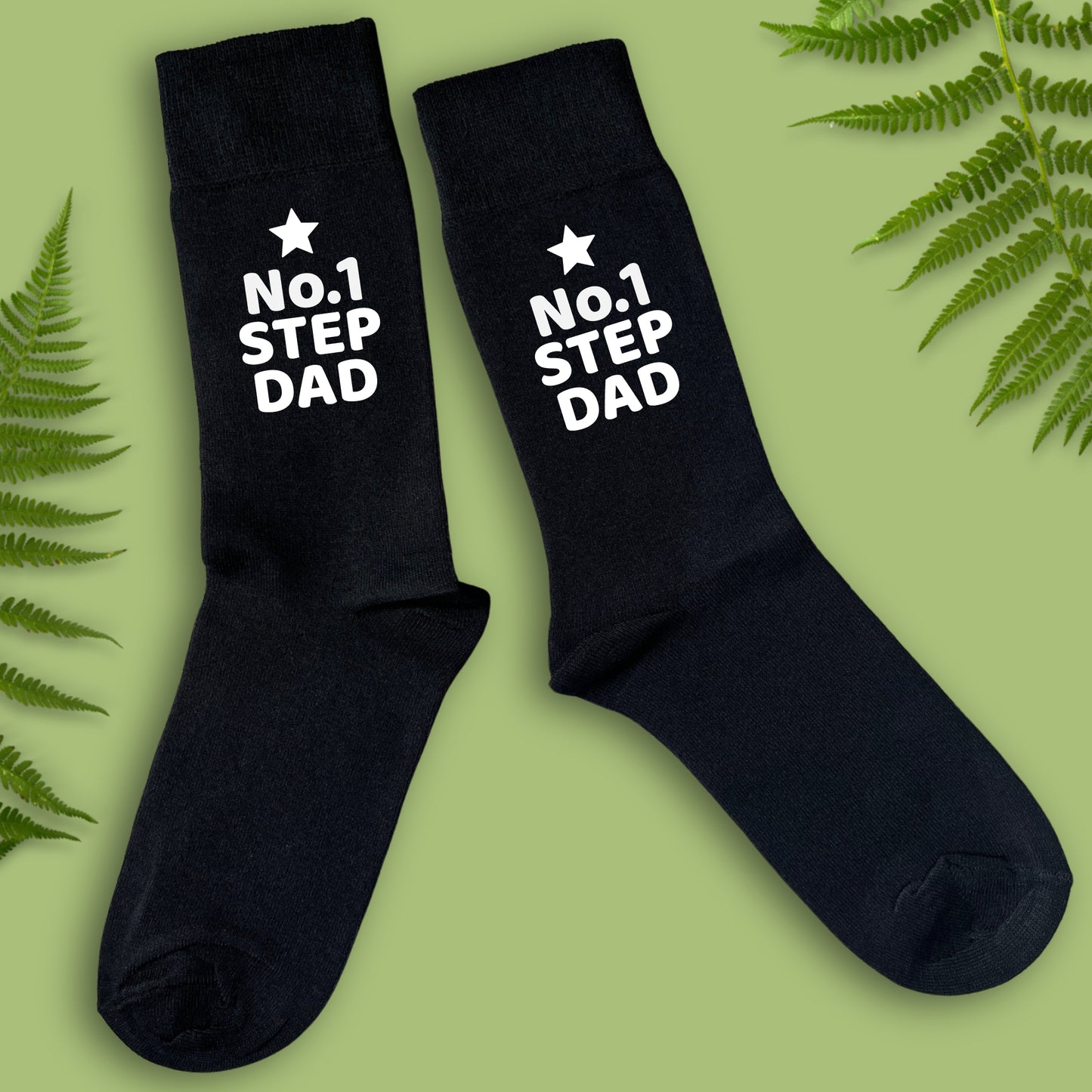 Black socks with 'No.1 Step Dad' text on a green background with fern leaves.
