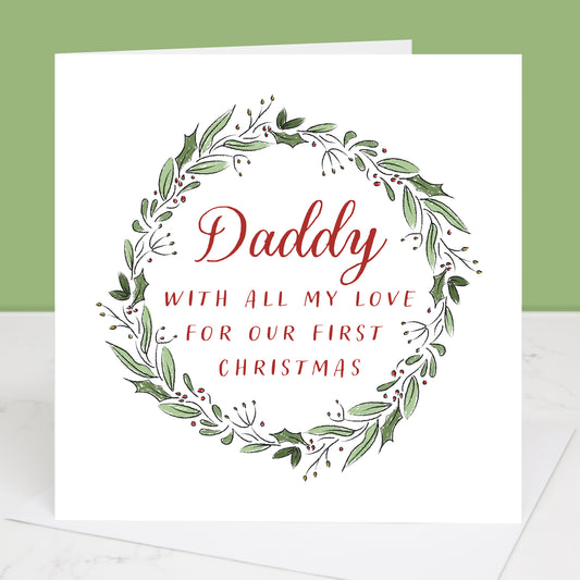 Greeting card with wreath design and text 'Daddy with all my love for our first Christmas' on a white background.
